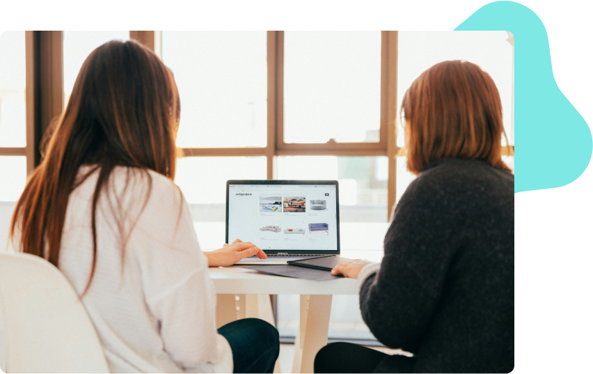 Two people sitting side by side working on a laptop with website screens in the viewport