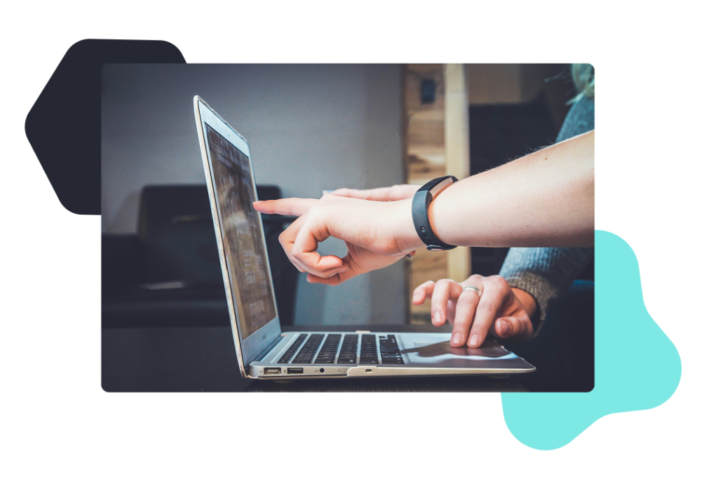 A person out of frame working on a laptop and pointing to something on the screen. 